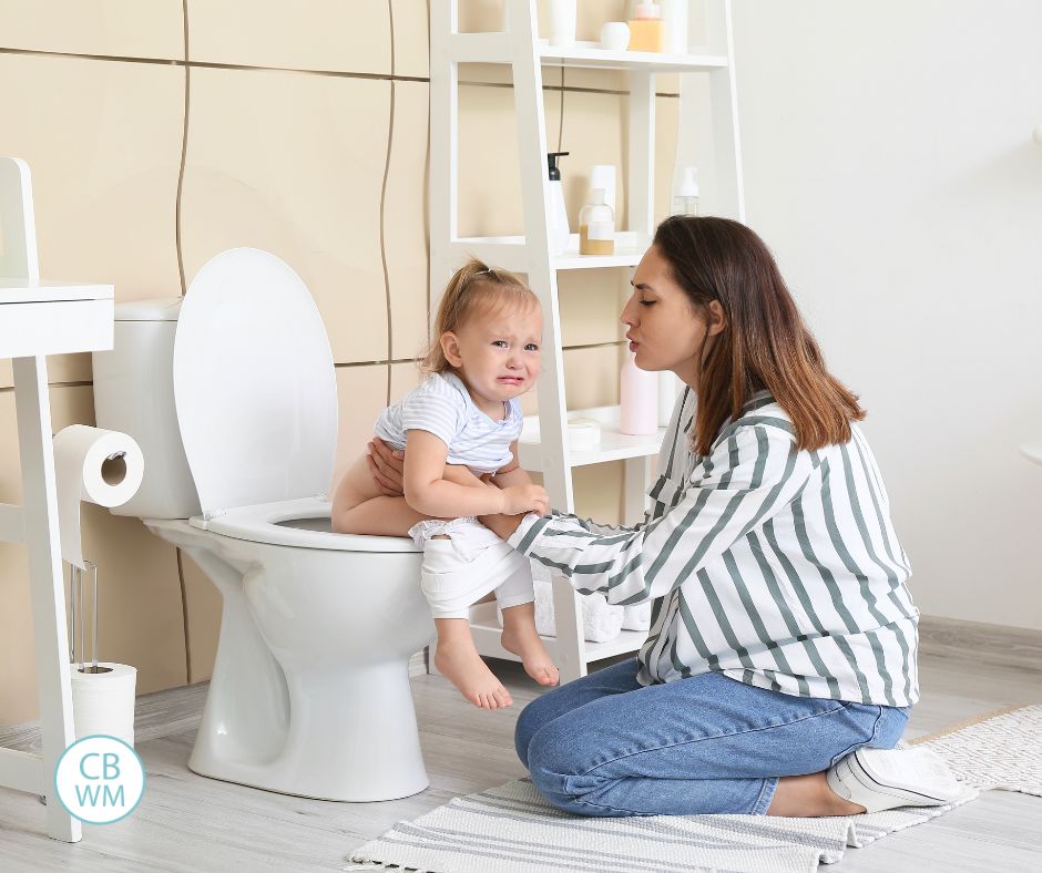 Mom holding toddler on the potty