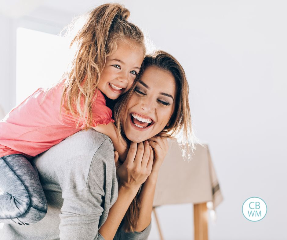 Mom with her daughter giving her a hug from behind