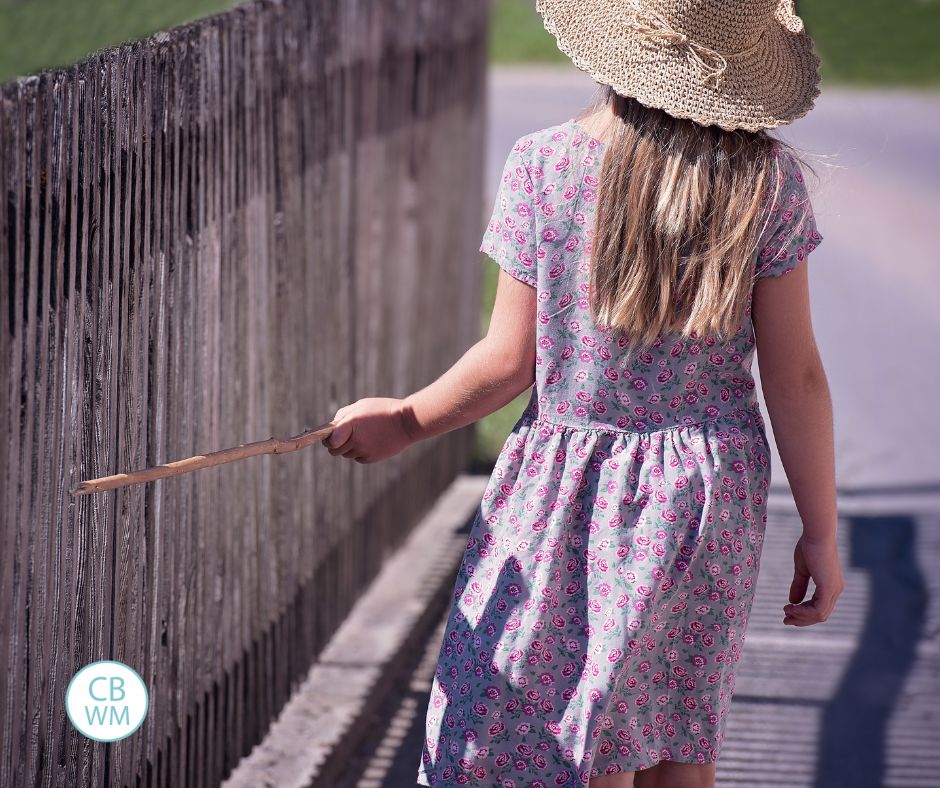 Child walking along a wood fence