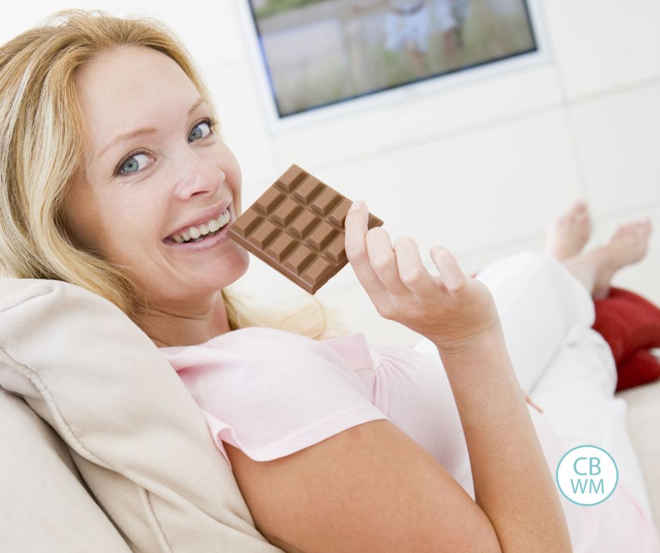 Woman holding a chocolate bar with a smile on her face