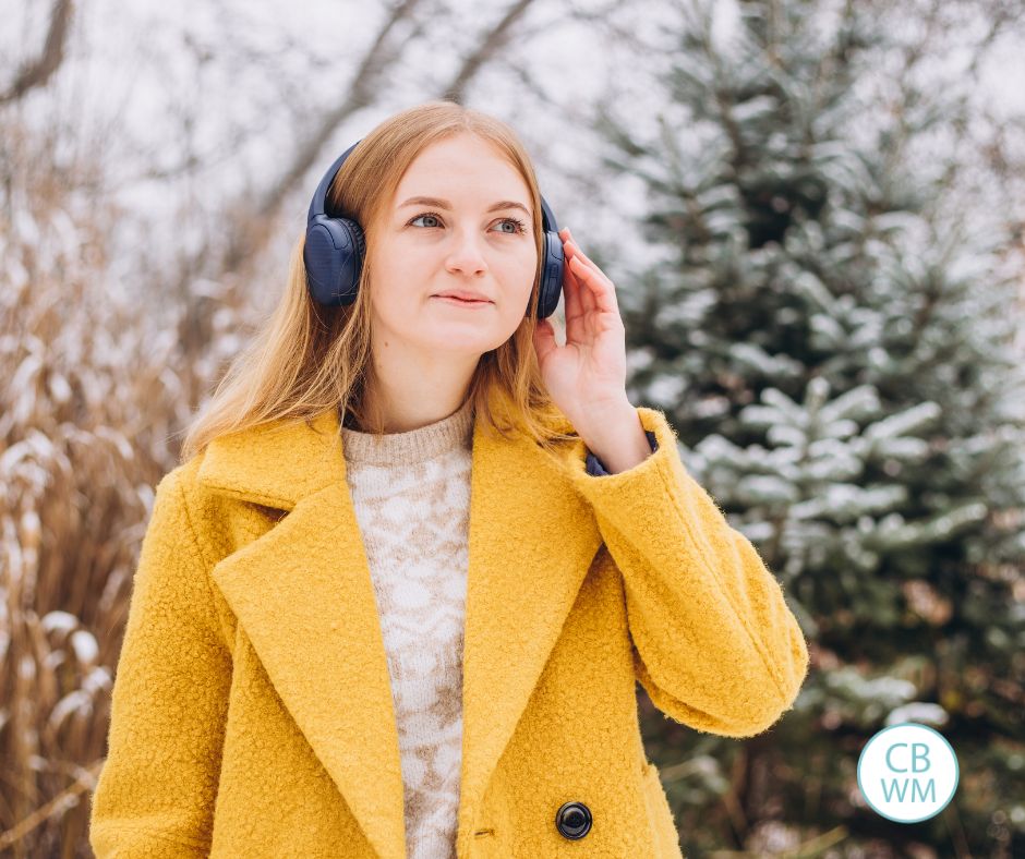 Woman wearing a yellow coat and listening to music on headphones