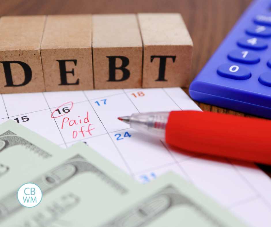 A photo with the word "DEBT" in blocks, a caluclator, some cash, a pen, and a calendar