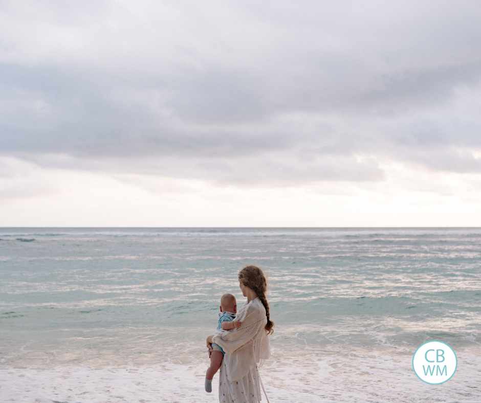 Mom and baby with the back to the camera looking out over the ocean