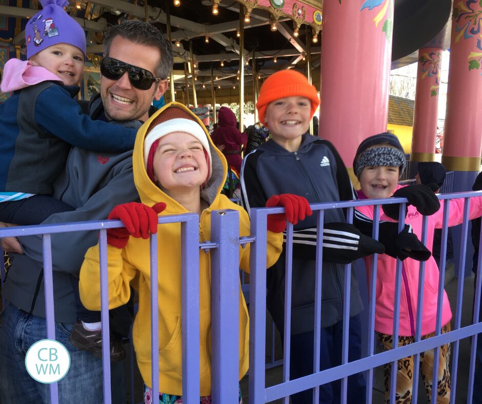 Nate with all of the kids waiting in line to ride a carousel 