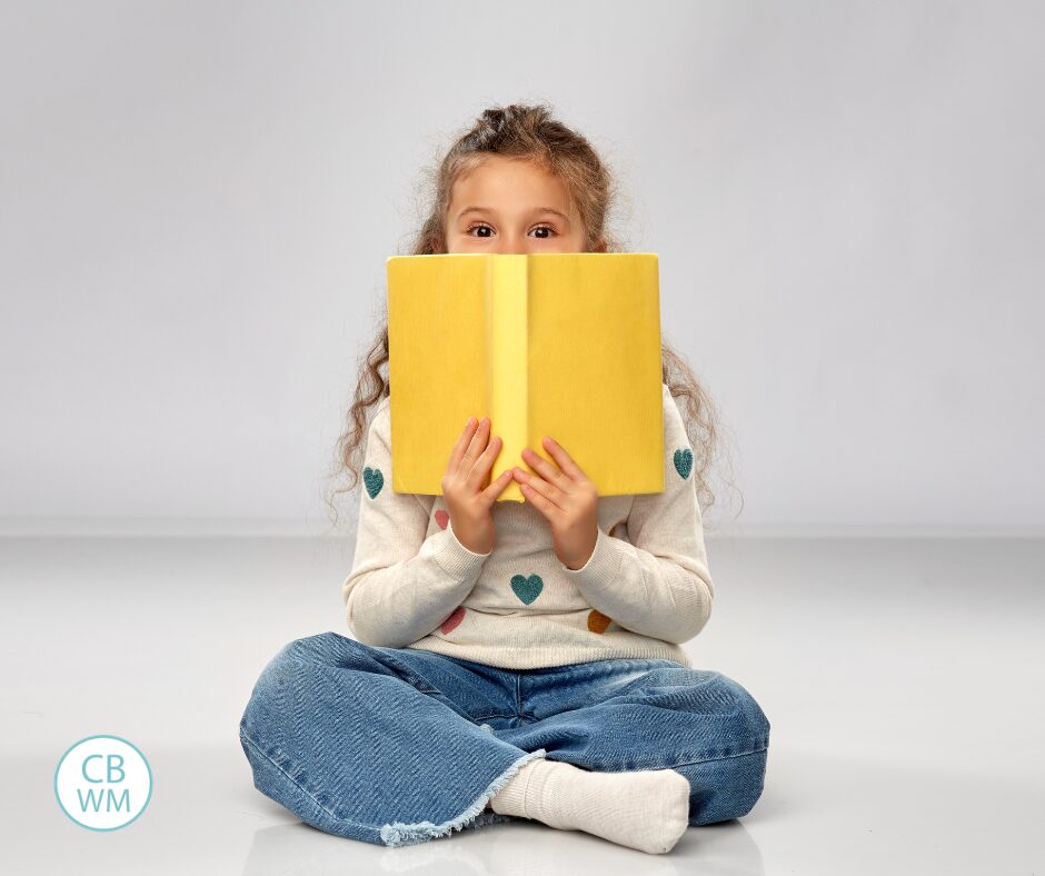 Girl holding a yellow book and covering half of her face
