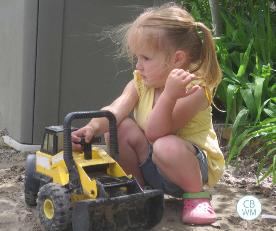Girl with tractor in sandbox