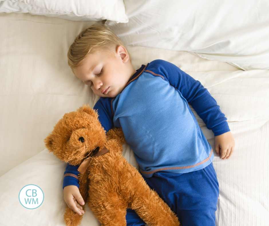 Toddler sleeping in bed with a stuffed bear