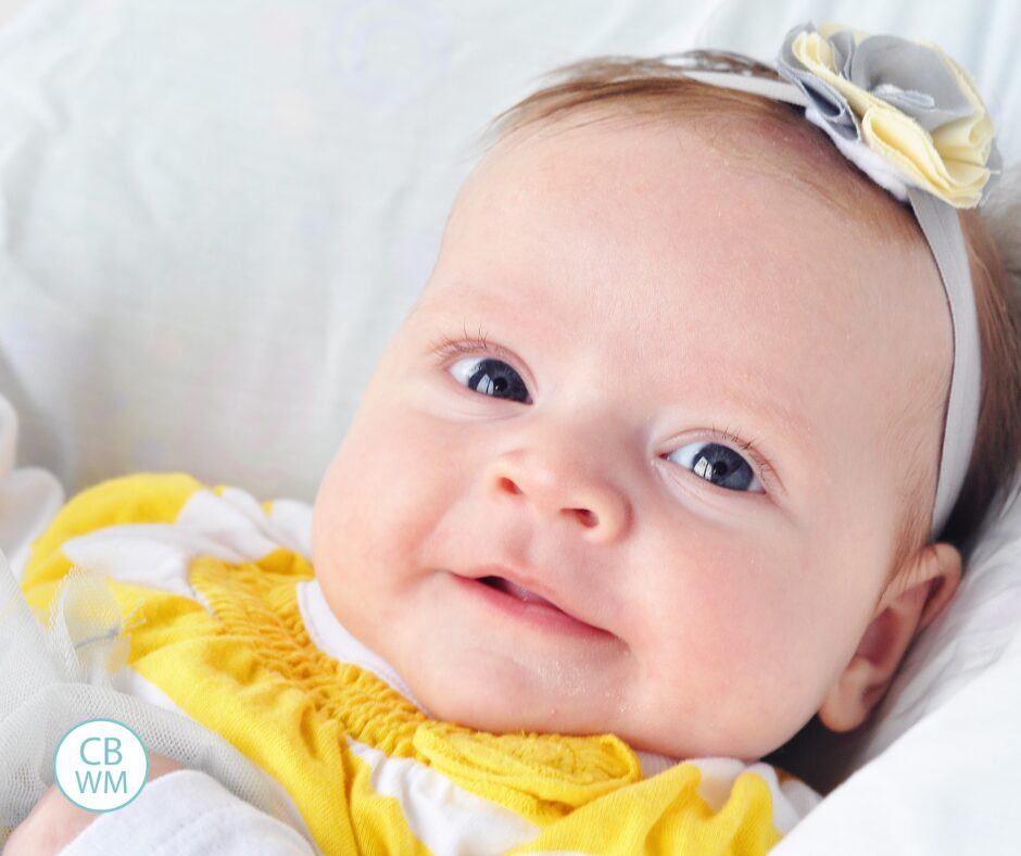 Brinley as a baby wearing yellow and white striped shirt with a bow in her hair