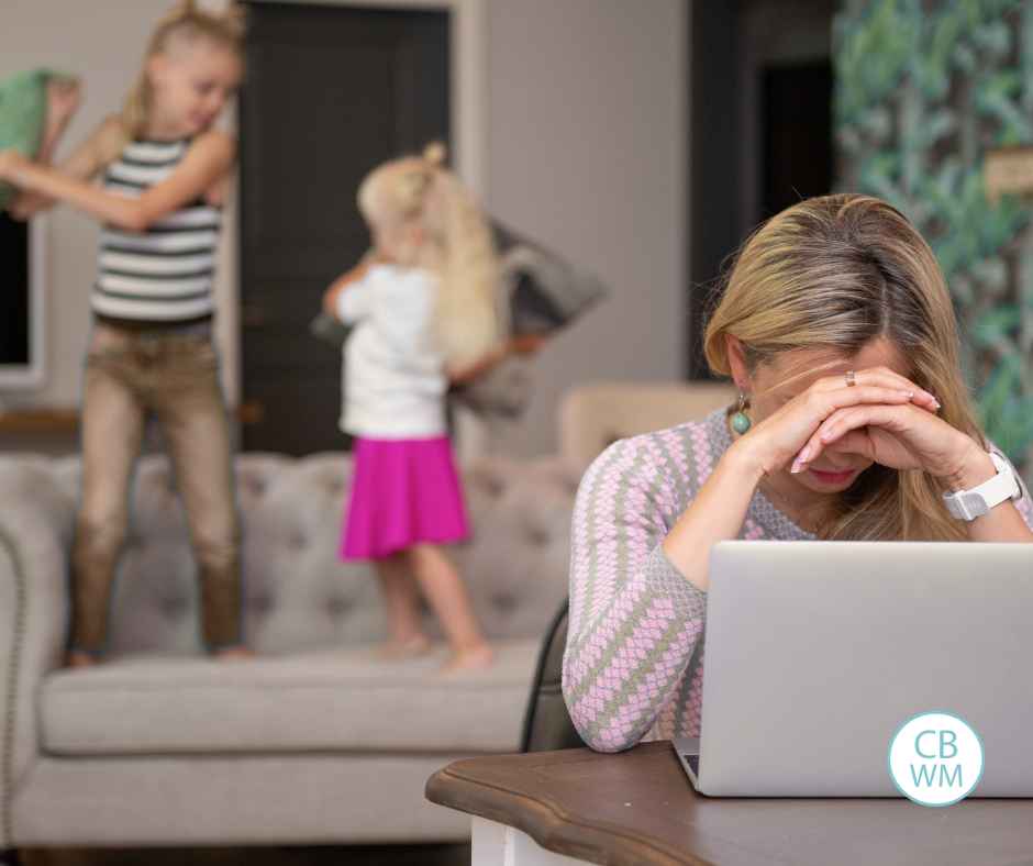 Mom stressed out with two kids behind her on the couch