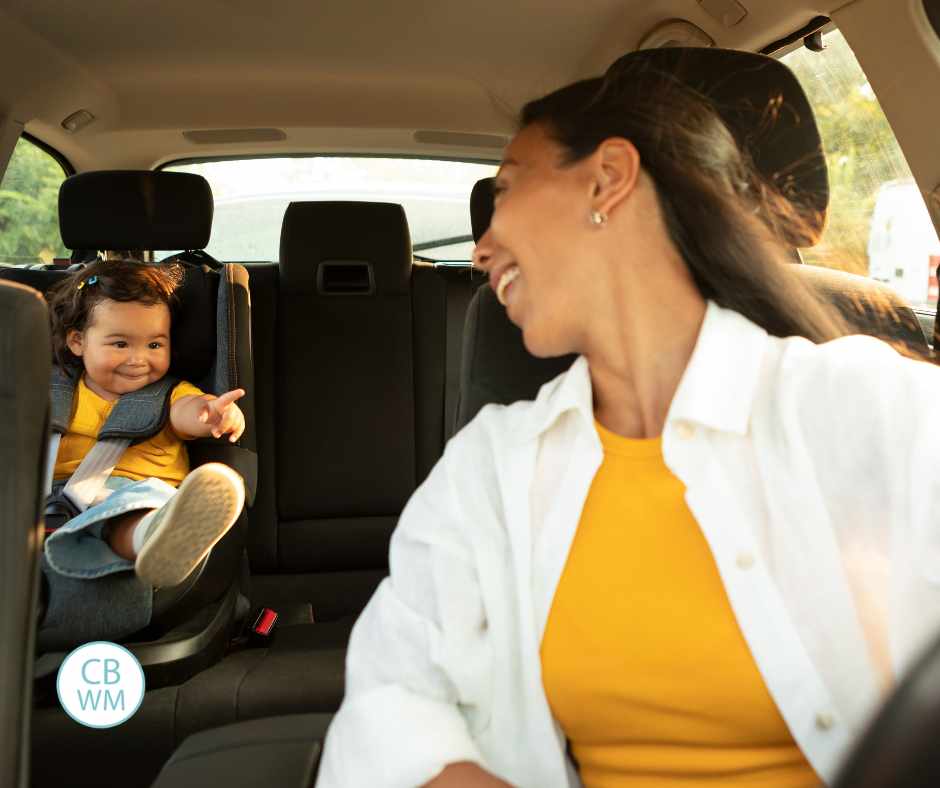 a mom in the car looking back at her baby in a carseat