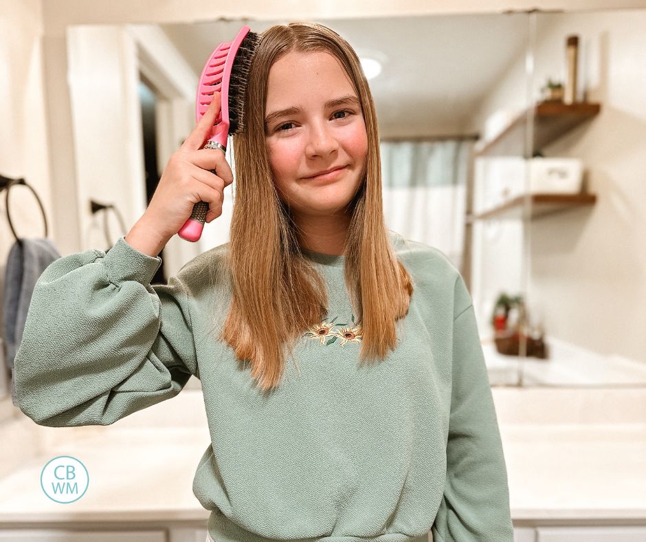 Brinley brushing her hair with the Tangles B. Gone brush