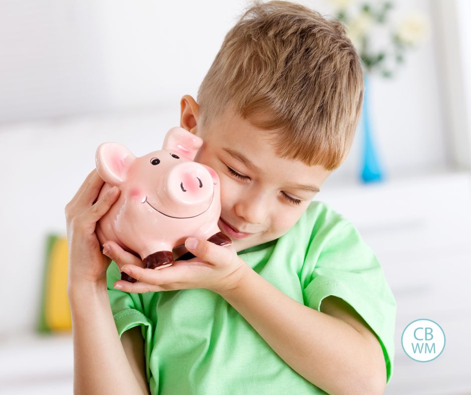 child hugging a piggy bank