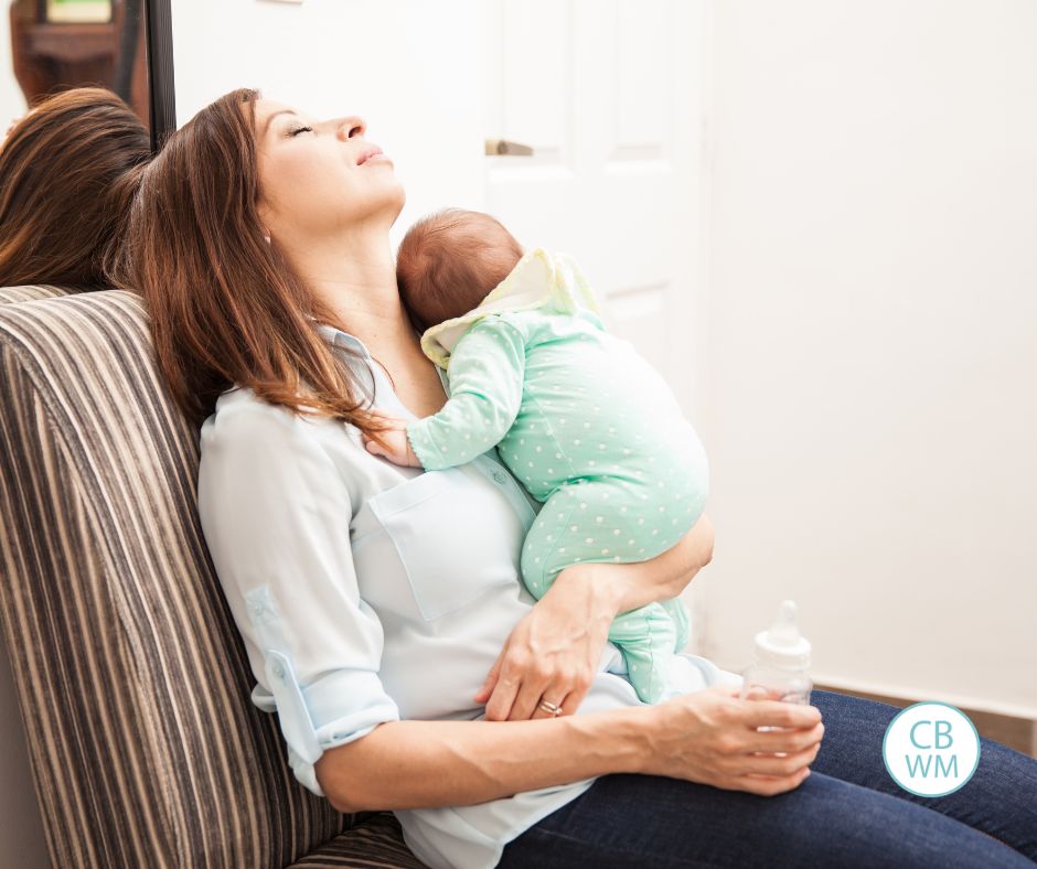 mom holding newborn baby. The mom is exhausted and worn out