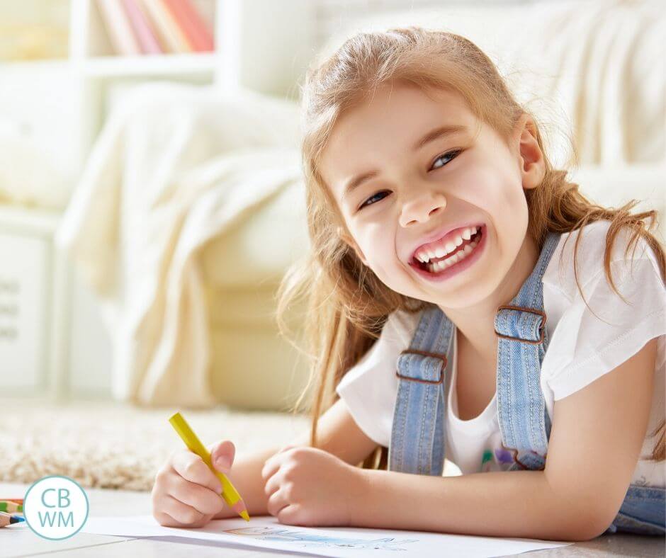 Girl on her tummy coloring and smiling