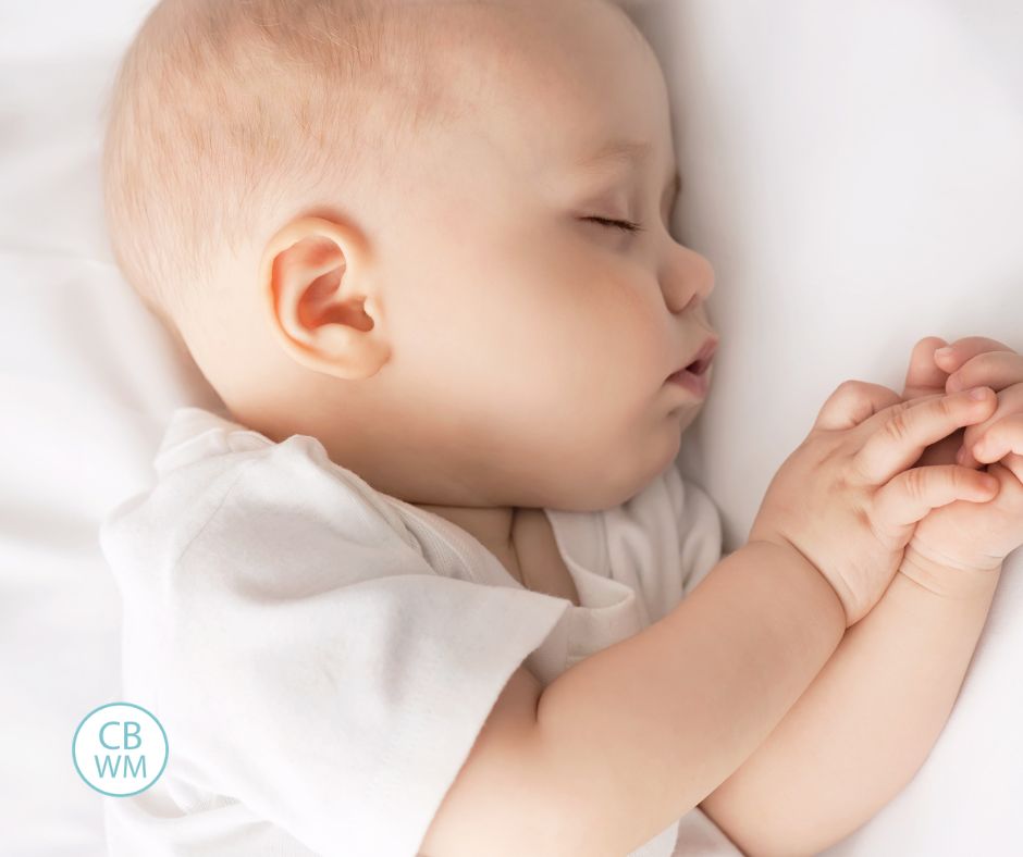 baby sleeping wearing a white onesie