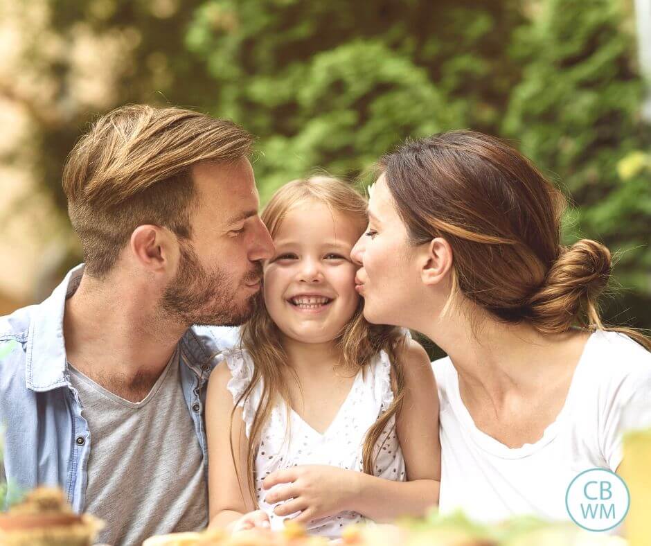 Father and Mother kissing daughter's face