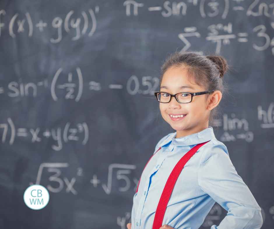 Child standing in front of a chalkboard with math problems on the board