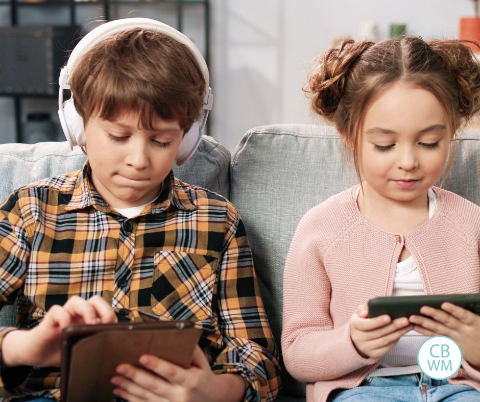 Brother and sister on devices sitting on the couch