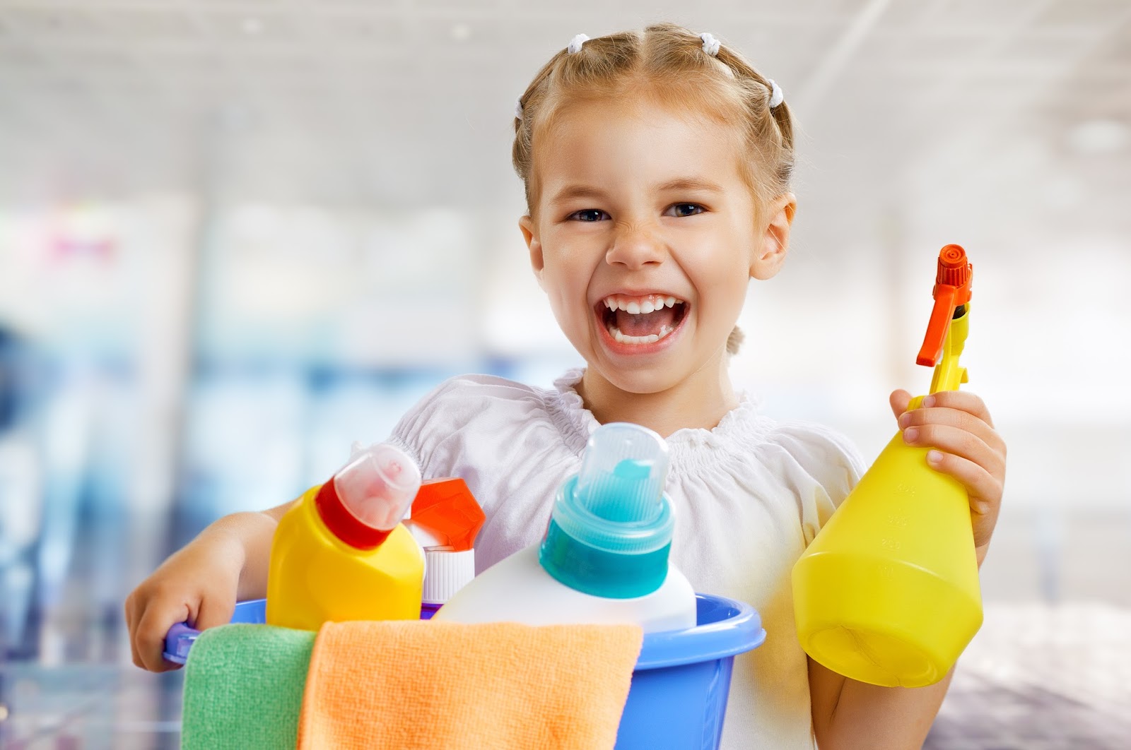 Young girl smiling and holding cleaning supplies