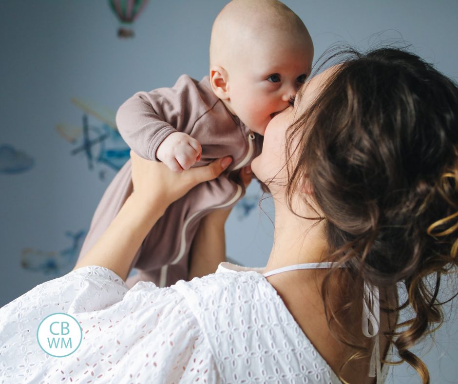 Mom holding baby up and kissing baby