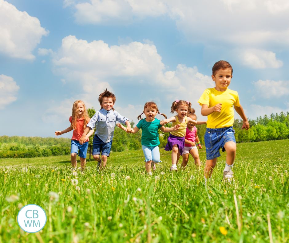 Kids running in open field. They are all wearing bright shirts.