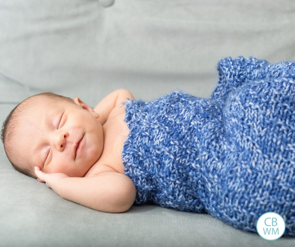 Baby sleeping on gray blanket with a blue blanket on top