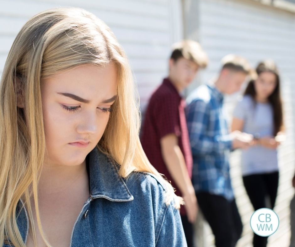 teen looking like she feels left out of a group of other teens