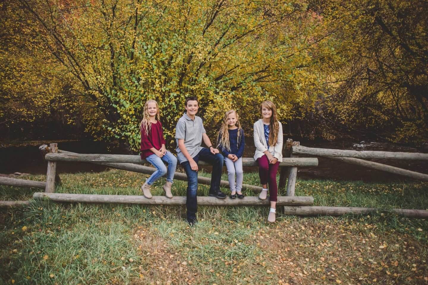 Family photos. Four children sitting on a fence