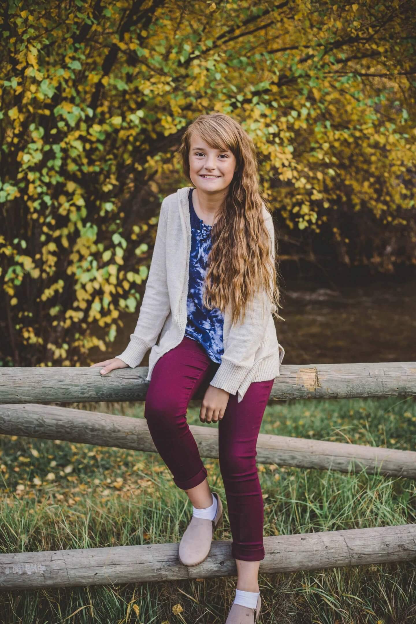 Preteen girl sitting on a fence