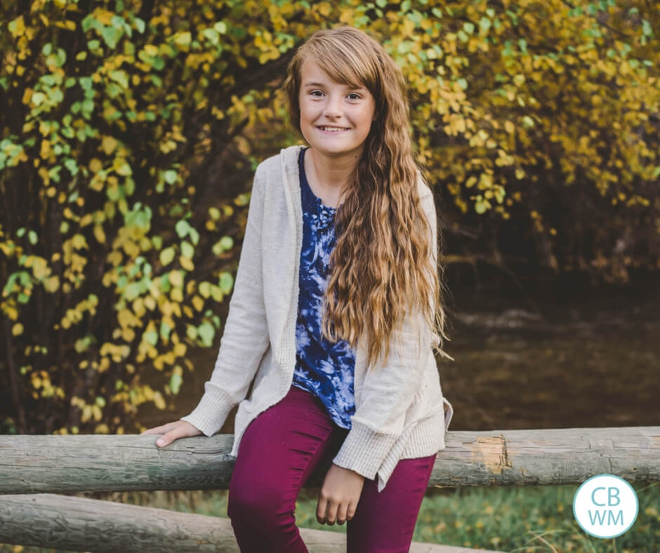 11.5 year old preteen girl sitting on a fence.