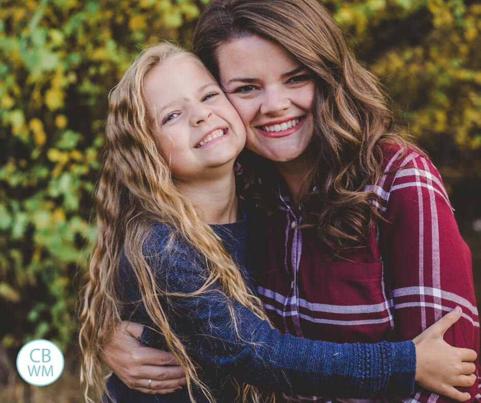 Mother and daughter hugging each other while sitting outdoors