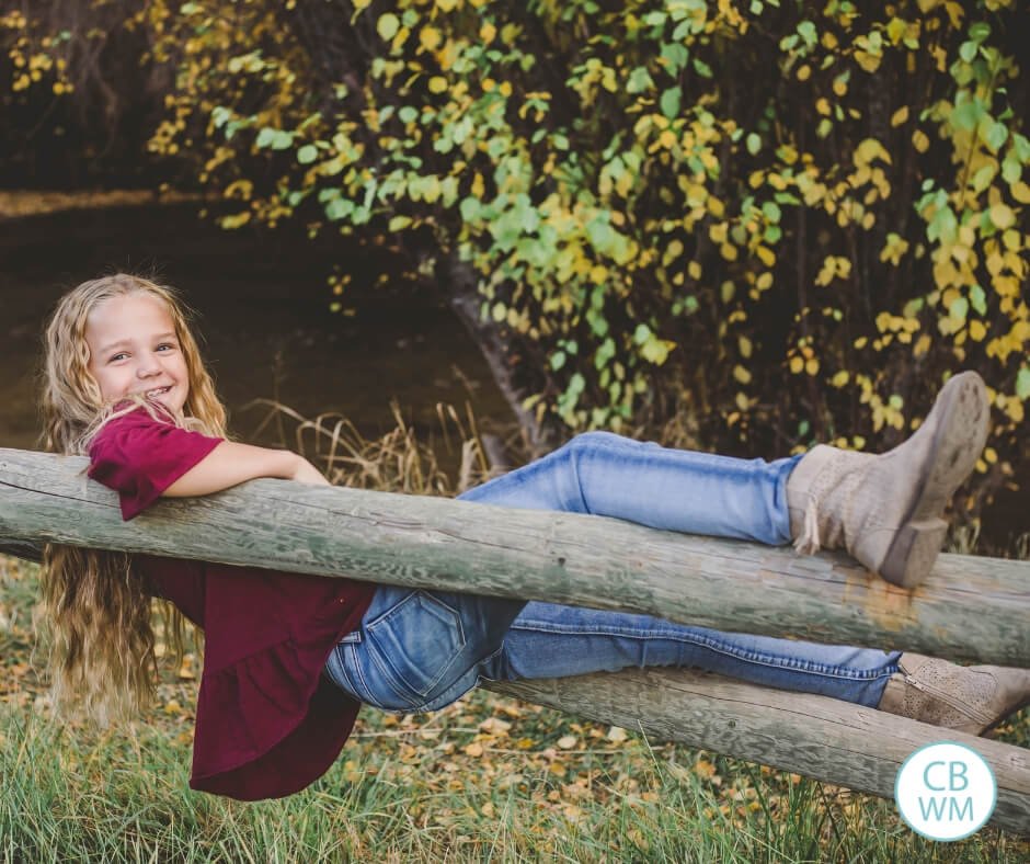 Girl sitting on a split rail fence