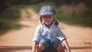 Boy sitting on a dirt road facing the camera