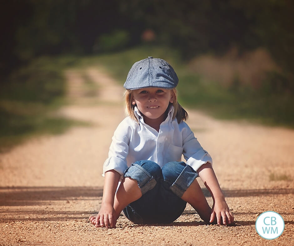 Boy sitting on a dirt road facing the camera