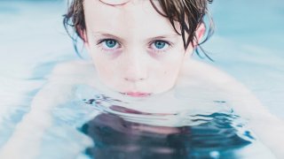 Boy with blue eyes staring at the camera while in the water
