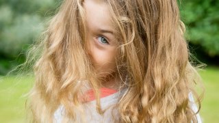 Girl looking over her shoulder while walking through grass