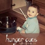 Baby boy sitting on the kitchen floor playing with pots and pans
