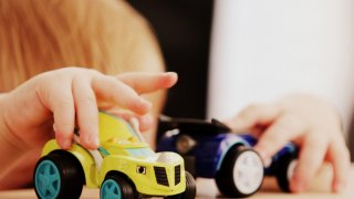 Child playing with toy cars at the table