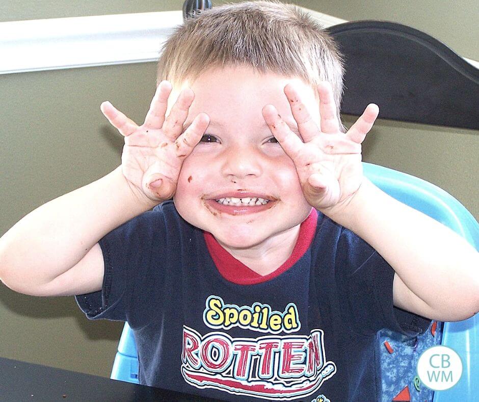 Boy holding hands up to face and smiling