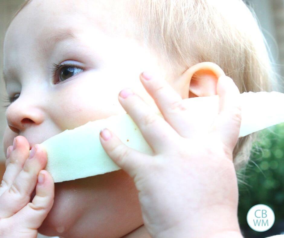 Baby eating a melon slice