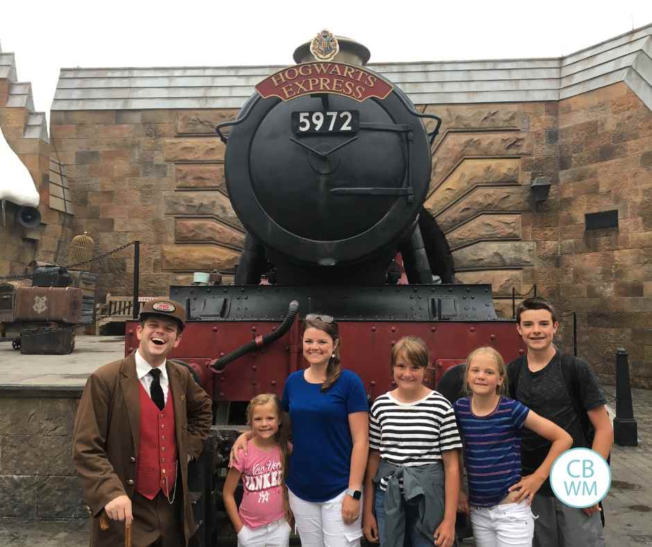Valerie and the kids standing in front of the Hogwarts Express train replica along with a conductor
