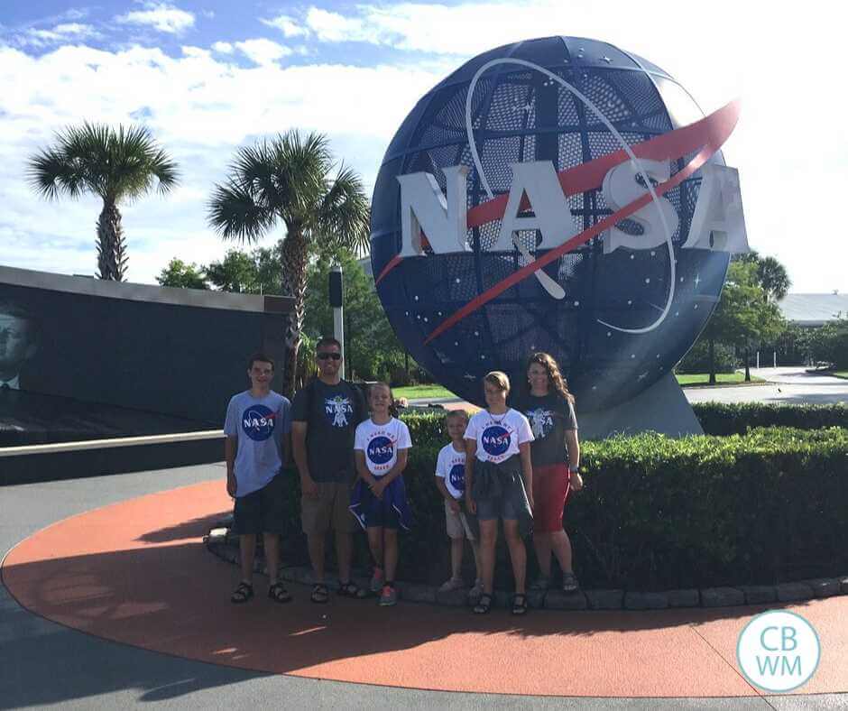 A family standing outside Kennedy Space Center in front of the NASA globe