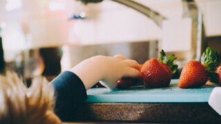 Child reaching for strawberry