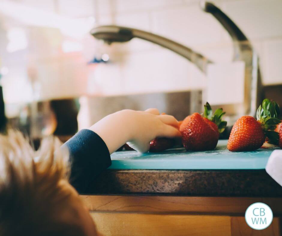 Child reaching for strawberry