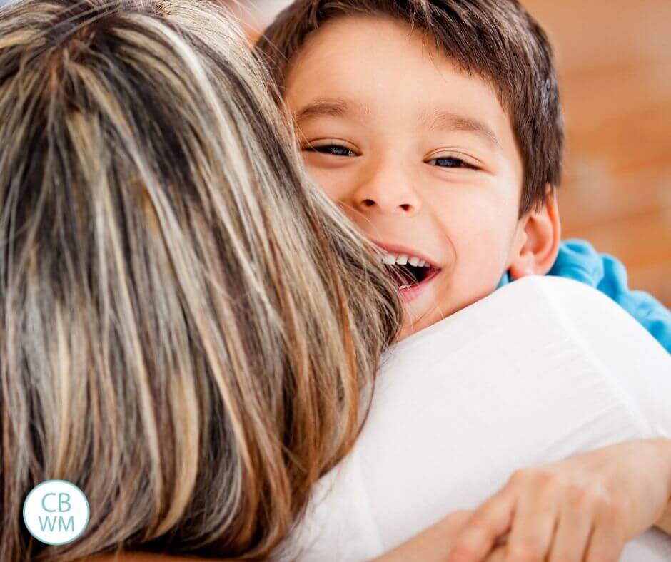 Boy smiling as he hugs his mom