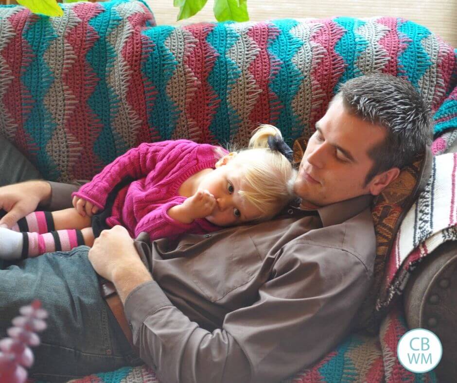 Young girl and her dad. The baby is showing her sleep cues but sucking her thumb. 