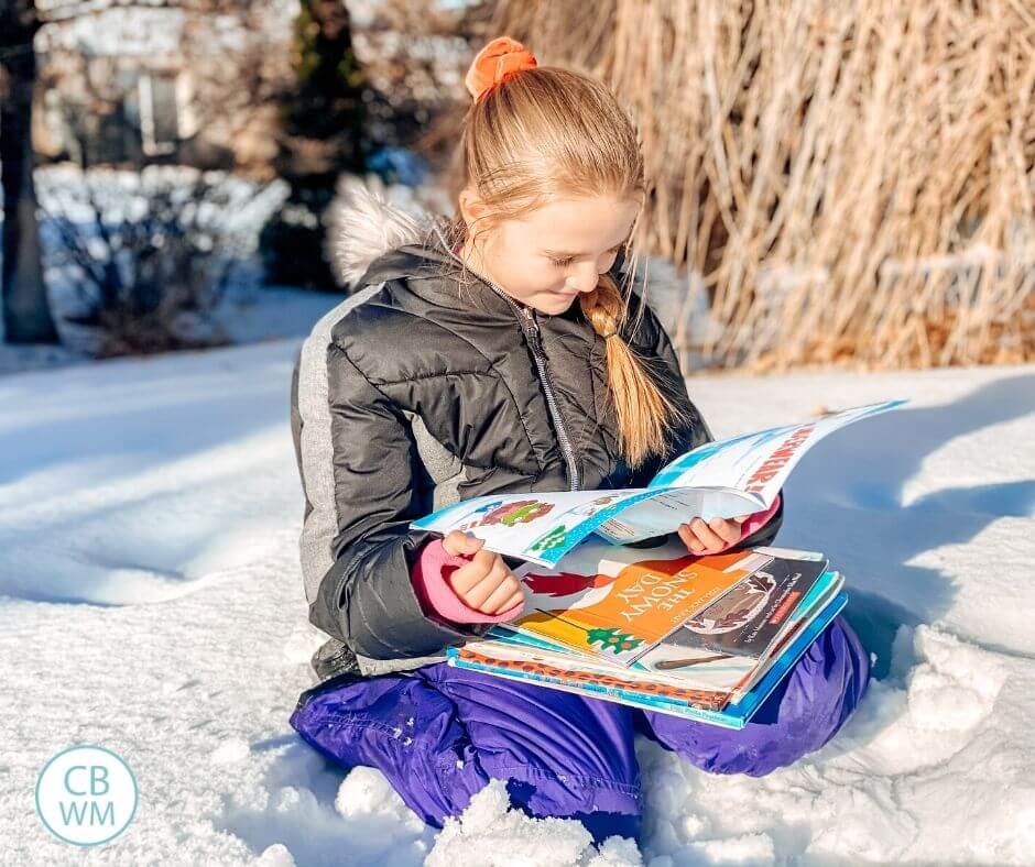 Child reading picture books in snow