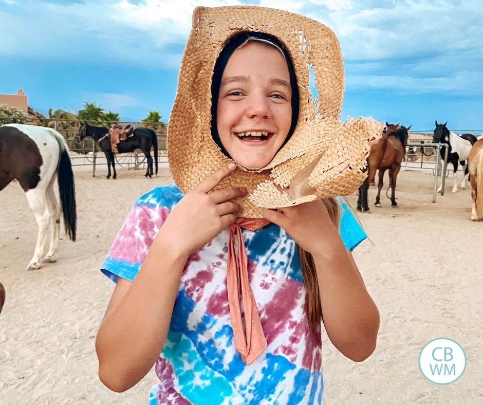 12 year old McKenna at a dude ranch holding a hat to her face