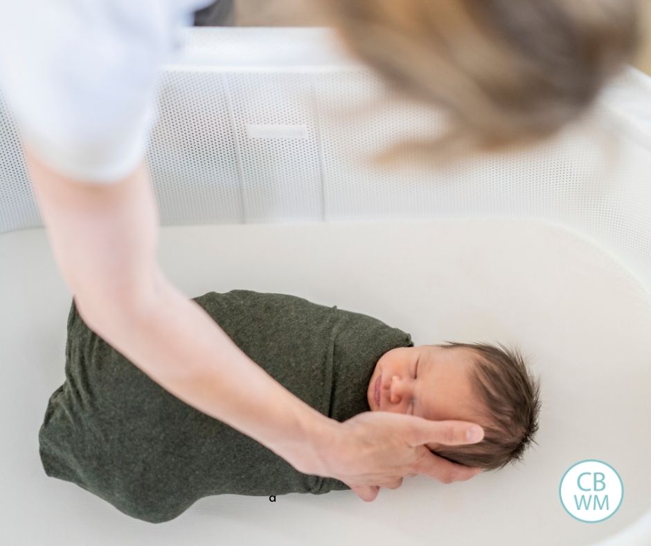 Mom putting baby to bed in bassinet