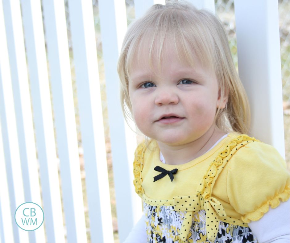 2 year old McKenna leaning against a fence